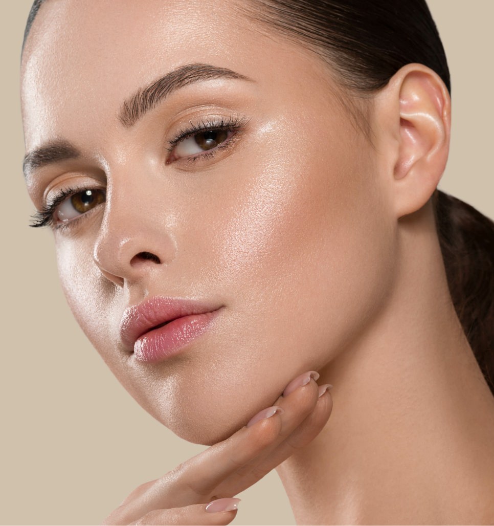 Woman with dark hair pulled back resting her fingers beneath her chin in a polished beauty portrait.