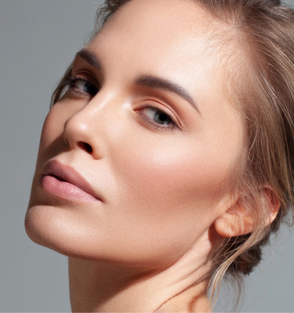 Woman with hair pulled back tilting her head slightly, highlighting her cheek and jawline contours.