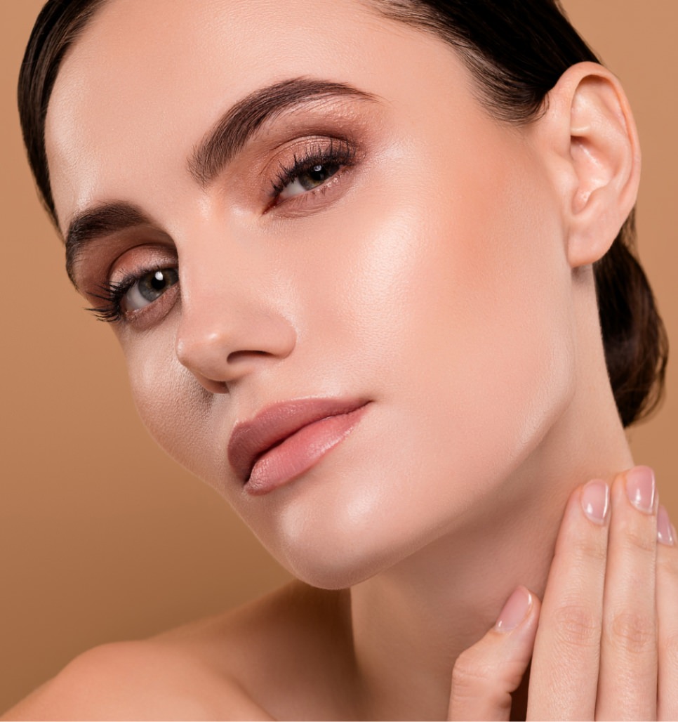 Woman with dark hair pulled back gently touching her neck in a polished beauty portrait highlighting smooth skin and facial contours.