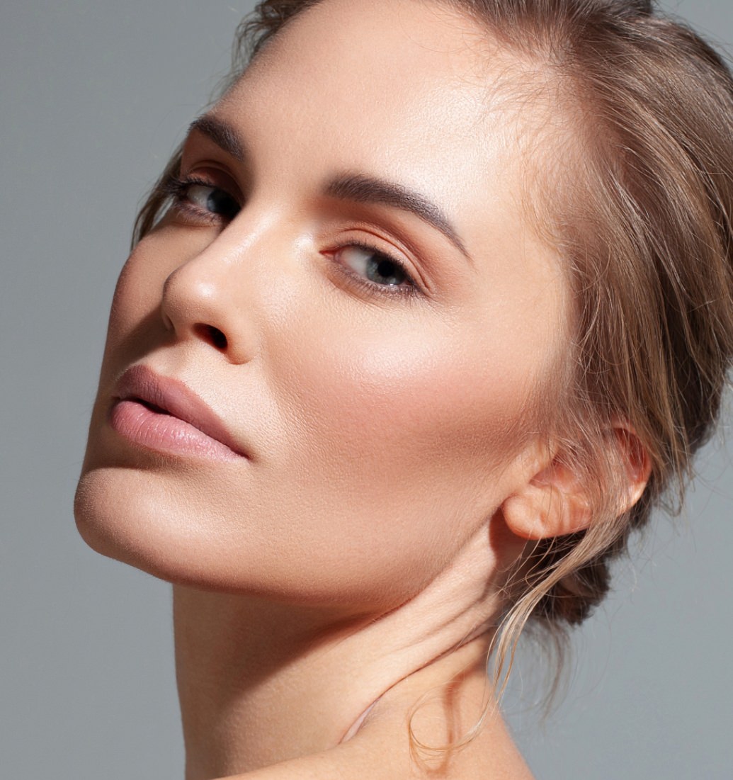Woman with brown hair pulled back, shown in a close-up portrait with her head slightly tilted